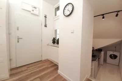 a white hallway with a clock on the wall at Cozy apartment by Wawel castel - G1b in Kraków