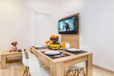 a dining room table with white chairs and a television at Bosacka old town apt - B17 in Kraków