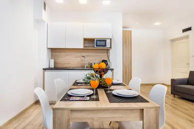 a dining room table with white chairs and a kitchen at Bosacka old town apartment - B28 in Kraków