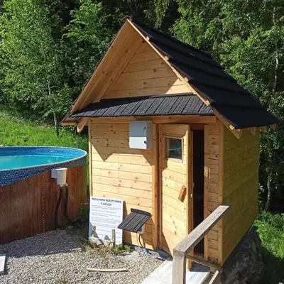 a wooden dog house next to a swimming pool at Zawoja domki z jacuzzi, domek w stylu góralskim in Zawoja
