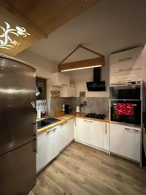a kitchen with white cabinets and stainless steel appliances at Zawoja domki z jacuzzi, domek w stylu góralskim in Zawoja