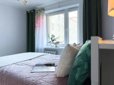 a bedroom with a bed with a book and a window at Apartament nieopodal Centrum Nauki Cogiteon in Kraków