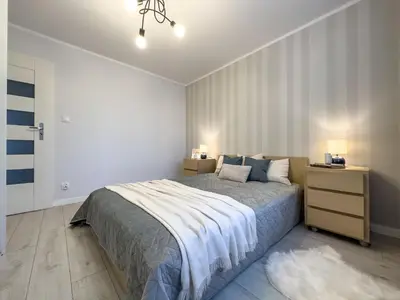 a bedroom with a bed and a night stand with two lamps at Apartament nieopodal Centrum Nauki Cogiteon in Kraków