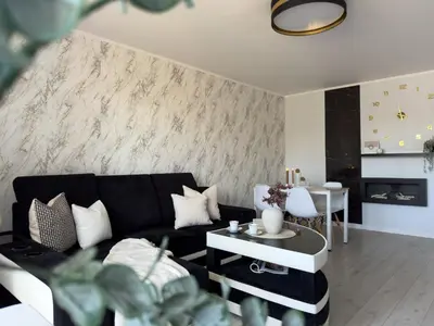 a living room with a black couch and a table at Apartament nieopodal Centrum Nauki Cogiteon in Kraków