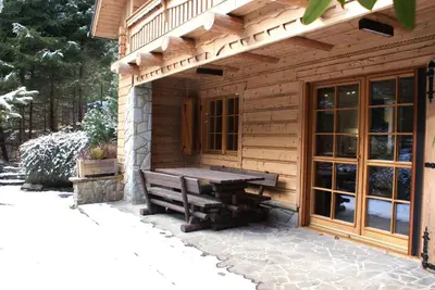 a wooden cabin with a bench in front of it at Forest House- dom nad górskim potokiem in Juszczyn