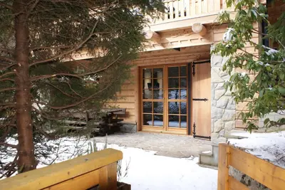 a house with a wooden door in the snow at Forest House- dom nad górskim potokiem in Juszczyn