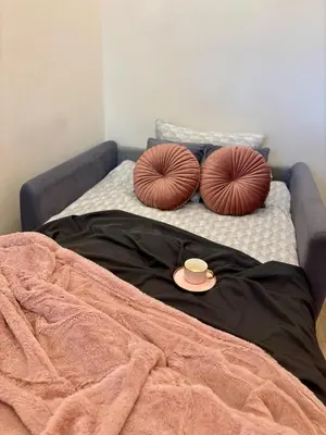a bed with two pillows and a cup on it at Vintage Lubicz Apartment in Kraków