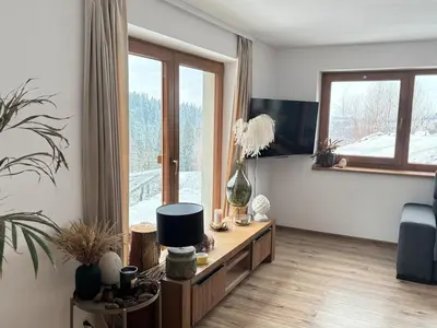 a living room with a tv and a table and a couch at Apartament pod lasem - przy szlaku na Turbacz, w pobliżu wyciągów narciarskich in Nowy Targ