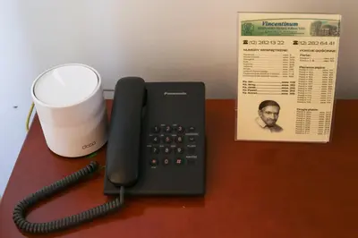 a telephone and a cup on a desk with a paper at Dom rekolekcyjny Vincentinum in Krzeszowice