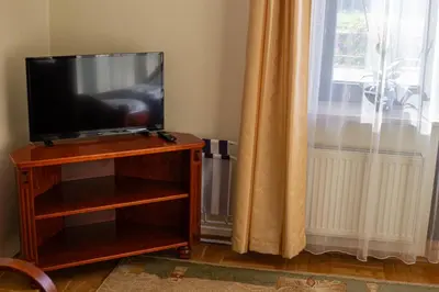 a flat screen tv sitting on a wooden stand next to a window at Dom rekolekcyjny Vincentinum in Krzeszowice