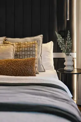 a bedroom with a bed with pillows and a black wall at Kazimierz Comfort Flat in Kraków