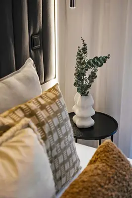 a vase with a plant on a table next to a bed at Kazimierz Comfort Flat in Kraków