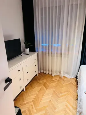 a bedroom with a television and a dresser with a bed at Biały Lotos in Kraków