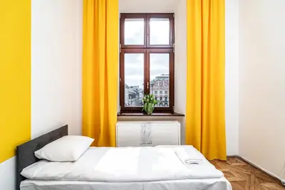 a bed in a room with yellow curtains and a window at ShortStayPoland Old Town C1 in Kraków