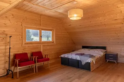a bedroom in a wooden cabin with a bed and two chairs at zDrzewaDom in Skrzydlna