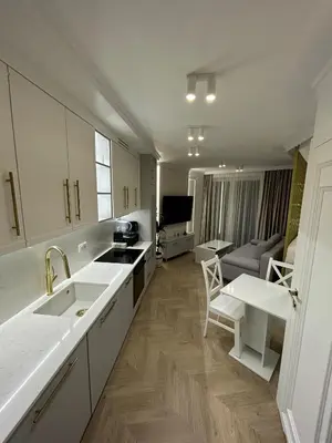 a kitchen with white cabinets and a living room at Krakow Center Stare Podgorze in Kraków