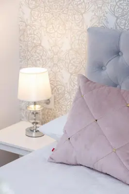 a bed with a purple pillow and a lamp at Nowoczesny Apartament w Centrum Krakowa by Noclegi Renters in Kraków