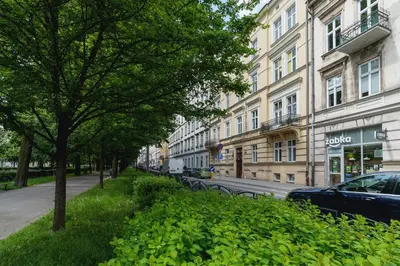 a street with trees and a car parked next to a building at Nowoczesny Apartament w Centrum Krakowa by Noclegi Renters in Kraków