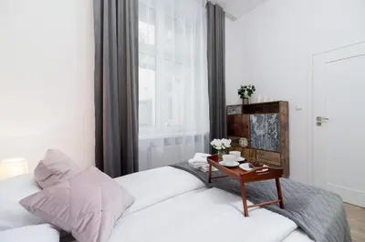 a bedroom with a white bed and a table at Nowoczesny Apartament w Centrum Krakowa by Noclegi Renters in Kraków