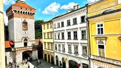 a stuffed animal sitting on a bed next to a window at Cinema Apartment with a view of Old Town in Kraków