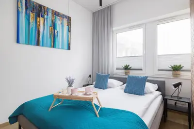 a bedroom with a bed and a table and windows at Turquoise Studio with Balcony & Air Conditioning Kraków by Noclegi Renters in Kraków