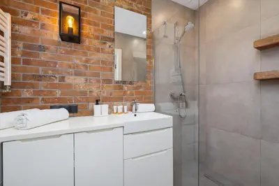 a bathroom with a white sink and a brick wall at Turquoise Studio with Balcony & Air Conditioning Kraków by Noclegi Renters in Kraków