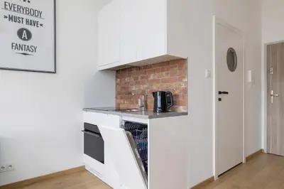 a kitchen with white cabinets and a brick wall at Turquoise Studio with Balcony & Air Conditioning Kraków by Noclegi Renters in Kraków