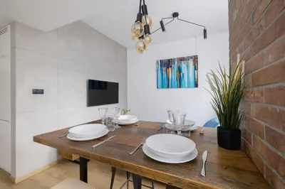 a dining room with a wooden table with white plates at Turquoise Studio with Balcony & Air Conditioning Kraków by Noclegi Renters in Kraków