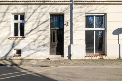 a white building with a door and two windows at Apartament Przyszłości z dwiema sypialniami w Krakowie by Noclegi Renters in Kraków