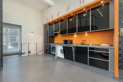 a kitchen with black cabinets and an orange wall at Apartament Przyszłości z dwiema sypialniami w Krakowie by Noclegi Renters in Kraków