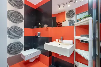 an orange and black bathroom with a sink and a mirror at Apartament Przyszłości z dwiema sypialniami w Krakowie by Noclegi Renters in Kraków