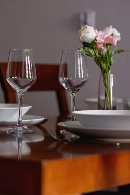 a table with two wine glasses and a vase of flowers at Asnyka Wyjątkowy Apartament w Centrum Krakowa by Noclegi Renters in Kraków