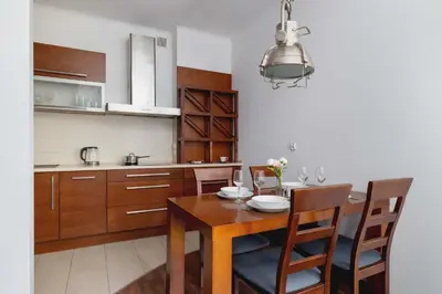 a kitchen with a wooden table and a dining room at Asnyka Wyjątkowy Apartament w Centrum Krakowa by Noclegi Renters in Kraków