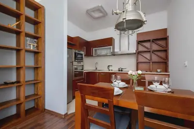 a kitchen with a wooden table and chairs and a dining room at Asnyka Wyjątkowy Apartament w Centrum Krakowa by Noclegi Renters in Kraków