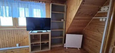 a living room with a television and a book shelf at SOWIA CHATKA- Stryszawa - domek z jacuzzi in Stryszawa