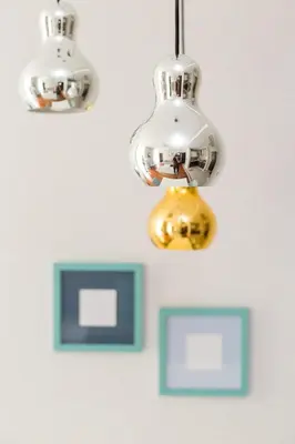 two lights are hanging on a wall with pictures at Pastel Apartment in Kraków