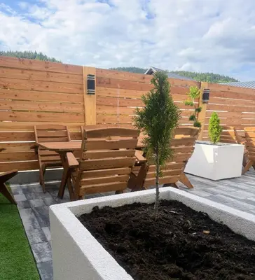 a patio with a wooden fence and a table and a tree at Domek za rzeką 2 in Zawoja