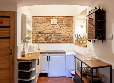 a kitchen with white cabinets and a brick wall at Apartment no5 Szlak street in Kraków