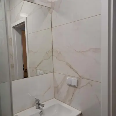 a white bathroom with a sink and a mirror at Apartament Słowackiego in Oświęcim