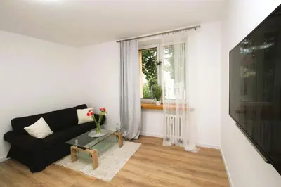 a living room with a black couch and a window at Apartament Słowackiego in Oświęcim