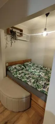 a bedroom with a bed and a ottoman at SmartApart in Kraków