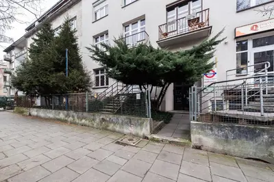 a building with a fence and trees in front of it at Underground Apartments by BookingHost in Kraków