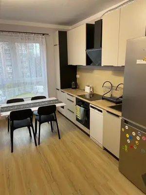 a kitchen with a table and chairs and a refrigerator at Illumina nowoczesny apartament 50m2, spokojna okolica, 25min do centrum in Kraków