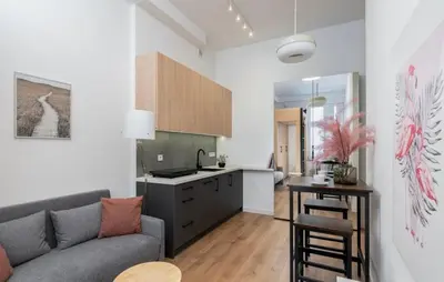 a living room with a couch and a kitchen at Lumi Loft Kraków in Kraków