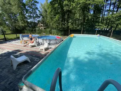 a man sitting in a chair next to a swimming pool at Zaskawie Apart in Wadowice