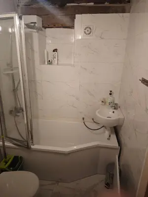 a white bathroom with a shower and a sink at oBłędny Domek in Zawoja