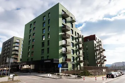 a green building with cars parked in a parking lot at Apartment with private terrace by NEARTO PL in Kraków