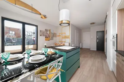 a kitchen with green cabinets and a table with plates on it at Apartment with private terrace by NEARTO PL in Kraków