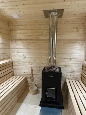 a sauna with a heater in a wooden room at Zielone Wzgórze- domki całoroczne Zawoja in Zawoja