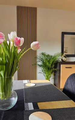 a vase of pink flowers sitting on a table at Apartament GOLD blisko Wawelu z DARMOWYM PARKINGIEM in Kraków